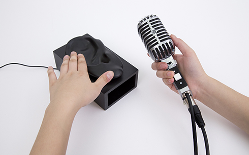 This amplification driver converts the sound loop into a high voltage, low current (~300 Vpp, ~50 mA) inaudible signal which is applied to the conductive metallic casing of the microphone via an additional connector. When holding the microphone, the visitor comes in contact with the inaudible, high voltage, low power version of the recorded sound. This creates a modulated electrostatic field around the person's body. When touching and sliding hand on an object such this modulated electrostatic field creates a very small vibrations. As a result, both the finger and the object together form a speaker, that makes the signal audible.